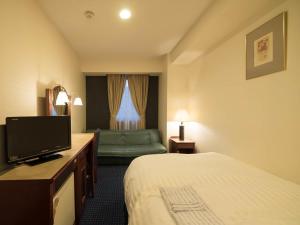 um quarto de hotel com uma cama e uma televisão de ecrã plano em Hotel Matsunoka Ichinoseki em Ichinoseki