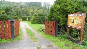 a sign on a fence next to a dirt road at Cztery Pory Roku - Domek 