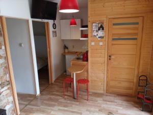 a small kitchen with a table and a stool in a room at Cztery Pory Roku - Domek 