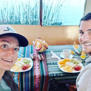 Ein Mann und eine Frau sitzen an einem Tisch mit Teller Essen. in der Unterkunft Uros Titicaca Khantaniwa Lodge in Puno