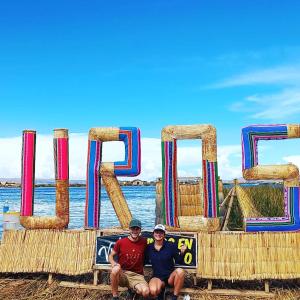 Zwei Männer sitzen vor einem Schild mit dem Ozean in der Unterkunft Uros Titicaca Khantaniwa Lodge in Puno