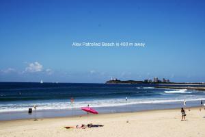 una spiaggia con ombrellone rosa e l'oceano di Alex Beach Cabins and Tourist Park ad Alexandra Headland