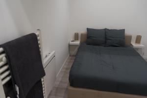 um pequeno quarto com uma cama e uma cadeira em Charmant appartement 2 pièces em Valence