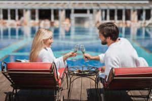 un homme et une femme buvant du vin au bord de la piscine dans l'établissement Alpenpark Resort Superior, à Seefeld in Tirol