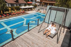 une mariée et un marié assis sur une balançoire près d'une piscine dans l'établissement Alpenpark Resort Superior, à Seefeld in Tirol