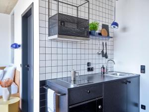 a black kitchen with a sink and a microwave at STAYERY Cologne Ehrenfeld in Cologne