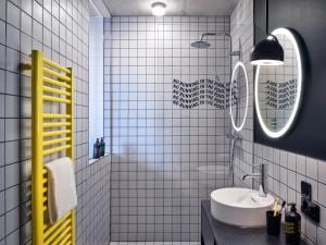 a white tiled bathroom with a sink and a mirror at STAYERY Cologne Ehrenfeld in Cologne