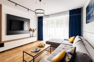 uma sala de estar com um sofá e uma televisão em KOBIELA Luxury Aparthotel KTW City Center em Katowice