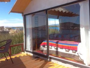 Zimmer mit einem Balkon und einem Bett auf einer Terrasse in der Unterkunft Uros Titicaca Khantaniwa Lodge in Puno