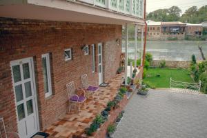 a brick house with chairs and a patio with a river at Hotel Paradise Road in Kutaisi