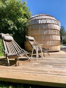 due sedie in legno sedute su una terrazza di legno con un edificio rotondo di Urlaub am Bahnhof ad Annaberg