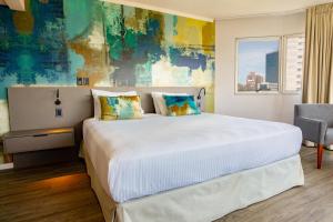 Un dormitorio con una gran cama blanca y una ventana en Palladium Business Hotel, en Montevideo