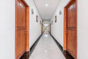 a hallway with wooden doors and white walls at Ganandra Stay Denpasar in Denpasar