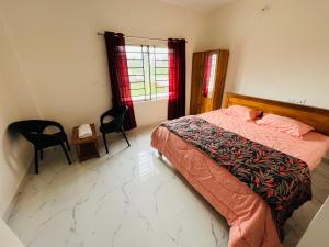 una camera con un letto e due sedie e una finestra di Darshan Arrive & Revive Homestay. a Kushalnagar