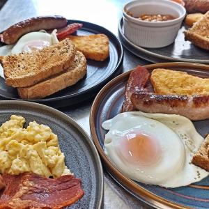 - une table avec des assiettes de produits pour le petit-déjeuner, des œufs au bacon et du pain grillé dans l'établissement Lodge Dinorwig, à Llanberis