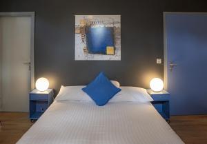 a bedroom with a blue pillow on a bed with two lights at Au Boeuf Rouge in Crassier