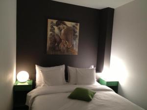 a bedroom with a large white bed with two lamps at Au Boeuf Rouge in Crassier