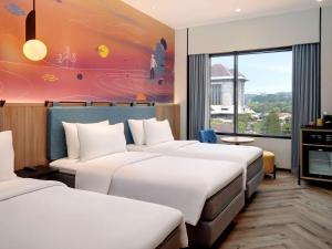 een hotelkamer met drie bedden en een schilderij bij ibis Styles Semarang Simpang Lima in Semarang