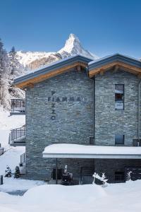 budynek z śniegiem na ziemi przed nim w obiekcie Apartment in Chalet Pizzo Fiamma w mieście Zermatt