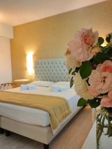 - une chambre avec un lit orné de fleurs roses dans un vase dans l'établissement Nuova Opera Rooms, à Vérone