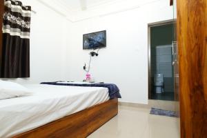 1 dormitorio con 1 cama y TV en la pared en Hillside Hideaway Gudalur, en Gūdalūr