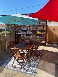 uma mesa de madeira e cadeiras debaixo de um guarda-sol em Oporto City Chalé no Porto