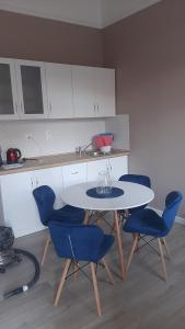 een keuken met een tafel en vier blauwe stoelen bij Glamour Apartman in Gyula