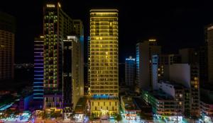 un edificio giallo alto in una città di notte di Queen Ann Nha Trang Hotel a Nha Trang