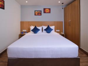 钦奈Essentia Premier Hotel Chennai OMR的卧室配有带蓝色枕头的大型白色床