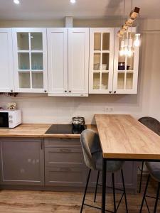 a kitchen with white cabinets and a wooden table at Апартаменты CLASSIC в жк Империал in Truskavets