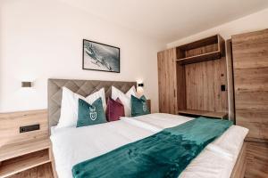 ein Schlafzimmer mit einem großen weißen Bett mit grünen Kissen in der Unterkunft Tanners Chalet Apartments in Altenmarkt im Pongau