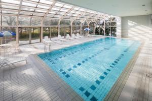 a large swimming pool in a building with a glass ceiling at HOTEL MYSTAYS PREMIER Narita in Narita