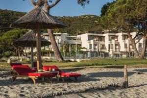 - un groupe de chaises et un parasol sur la plage dans l'établissement Hôtel La Roya, à Saint-Florent