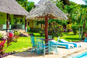 une terrasse avec des chaises, une table et un parasol dans l'établissement Oasis Diani Beach Villas, à Diani Beach