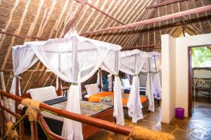 une chambre avec un groupe de lits dans une cabane en paille dans l'établissement Oasis Diani Beach Villas, à Diani Beach