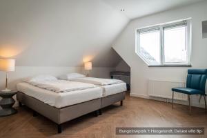 1 Schlafzimmer mit 2 Betten und einem blauen Stuhl in der Unterkunft Bungalowpark 't Hoogelandt in De Koog