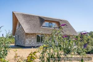 ein kleines Backsteinhaus mit einem Strohdach in der Unterkunft Bungalowpark 't Hoogelandt in De Koog