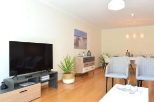 uma sala de estar com uma televisão de ecrã plano e uma mesa em Machico Beach, a Home in Madeira em Machico