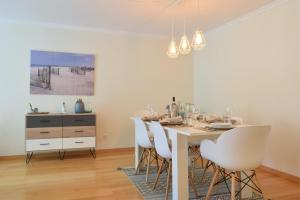 uma sala de jantar com uma mesa branca e cadeiras brancas em Machico Beach, a Home in Madeira em Machico