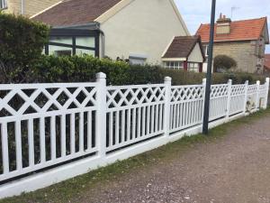 ein weißer Gartenzaun vor einem Haus in der Unterkunft Luc sur mer in Luc-sur-Mer