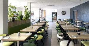 a dining room with wooden tables and green chairs at ATOLON PARK HOTEL in Brumath