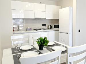 uma cozinha branca com uma mesa de jantar e armários brancos em OASIS, Charming 1BD apartment with living room em Chişinău