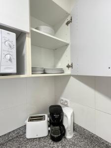 eine Küche mit weißen Schränken, einem Toaster und Geräten in der Unterkunft Apartamentos Venecia in Lloret de Mar