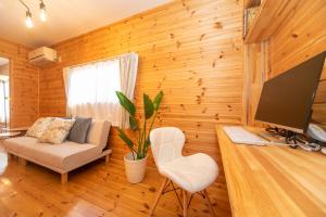 a living room with wooden walls and a television and a couch at Yokkaichi Motomachi Hotel in Yokkaichi