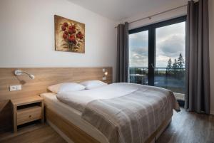 - une chambre avec un lit et une grande fenêtre dans l'établissement TATRYSTAY Armeria Apartments, à Štrbské Pleso