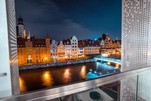 - un balcon offrant une vue sur la ville la nuit dans l'établissement CLASSY APARTMENTS - Gdańsk - Widok z Wyspy, à Gdańsk