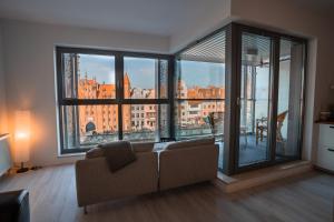 - un salon avec un canapé et de grandes fenêtres dans l'établissement CLASSY APARTMENTS - Gdańsk - Widok z Wyspy, à Gdańsk