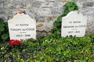 two signs on a stone wall with flowers and plants at Au Bord de l'Oise in Auvers-sur-Oise