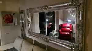 a mirror on a wall with a red chair in a room at Stunning Holiday Home. Free Parking. in Manchester