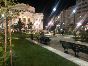 une personne assise sur un banc dans un parc la nuit dans l'établissement Royal Blue Grand Suite No 2, au Pirée